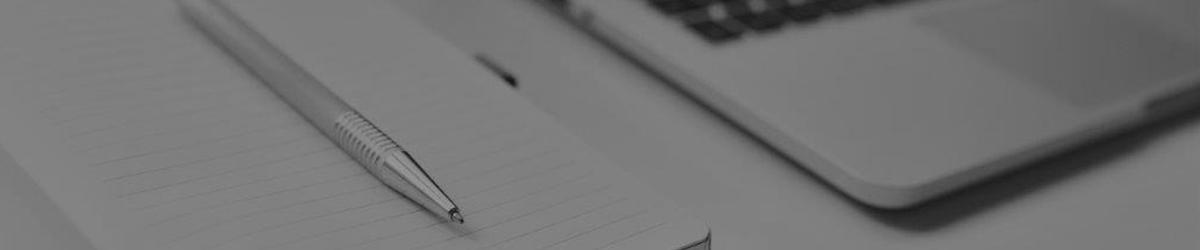 Block und Stift neben Laptop Tastatur