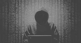 Person mit Hoodie am Laptop vor Hintergrund mit vielen Zahlen und Buchstaben